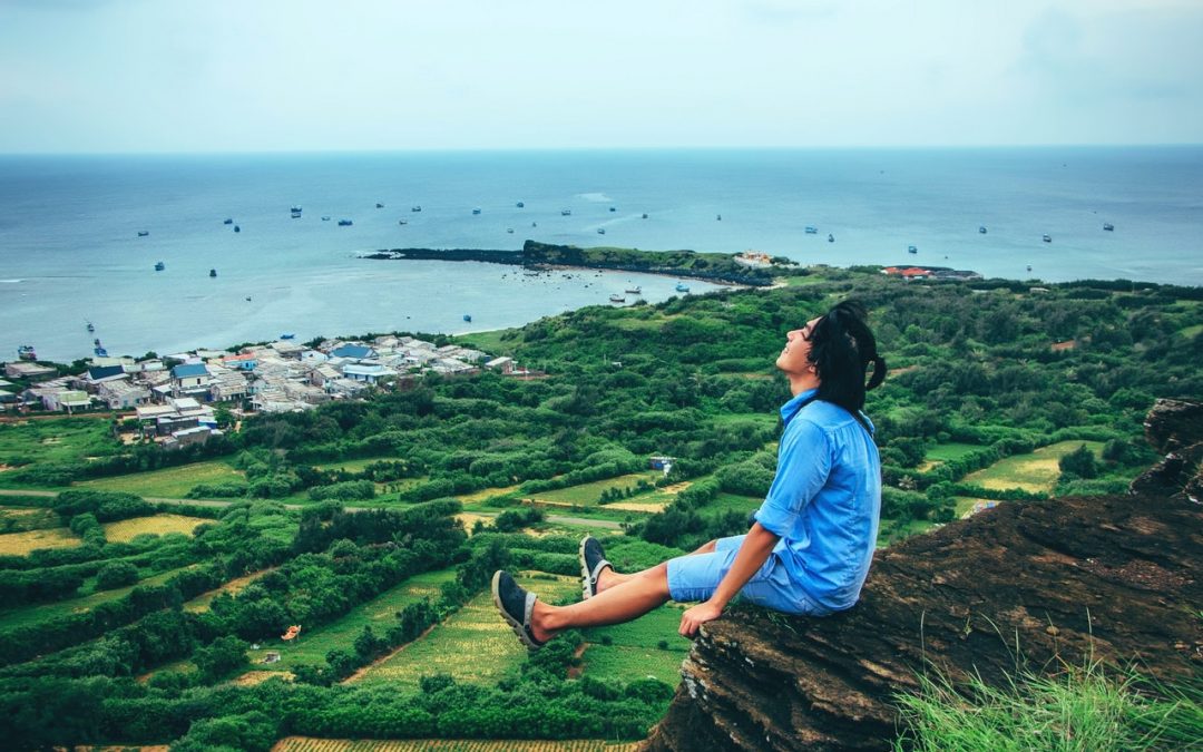 Man sitting on cliff overlooking town