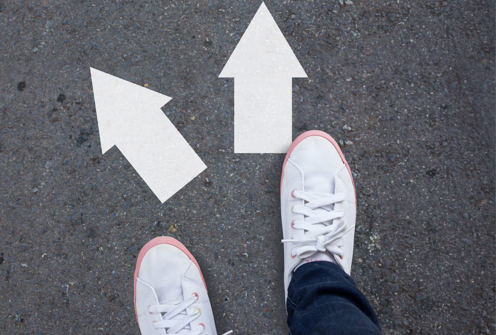 Pair of shoes standing on a tarmac road with two arrows