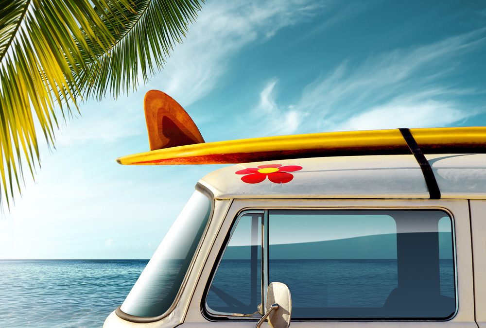 Detail of a vintage van in the beach with a surfboard on the roof