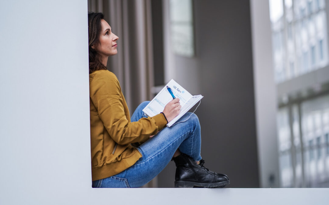 Woman sitting with a journal looking pensive